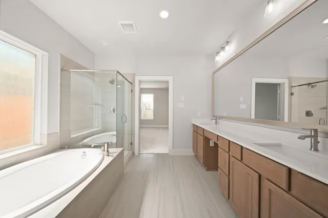 a spacious bathroom with a tub sink shower and mirror