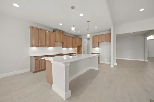 a large kitchen with a large counter top a sink stainless steel appliances and cabinets