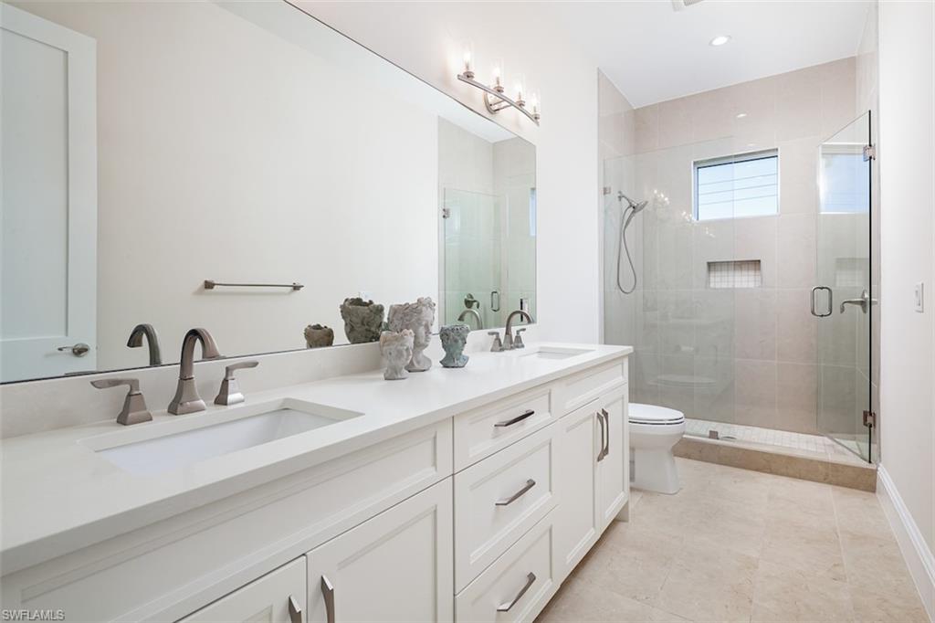 2879 Coco Lakes Drive Naples, FL 34105 - Photo 23 of 30 a bathroom with a double vanity sink toilet mirror and shower