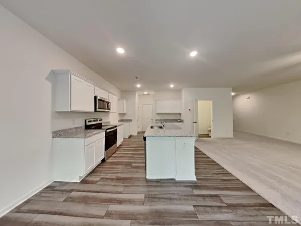 a large white kitchen with kitchen island a sink white cabinets and stainless steel appliances