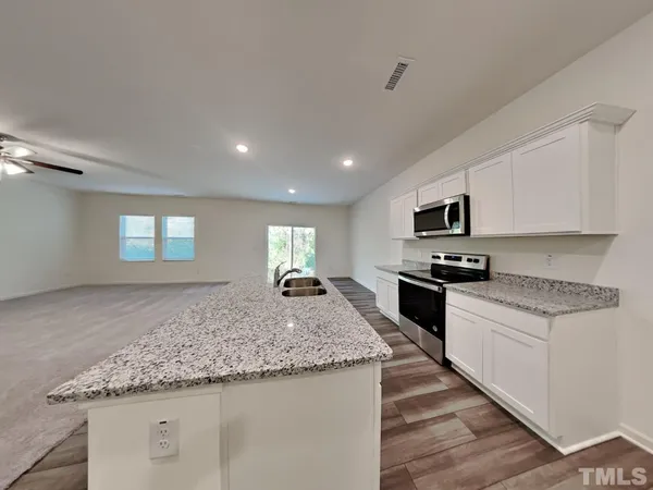 a kitchen with stainless steel appliances granite countertop a stove a sink and a microwave
