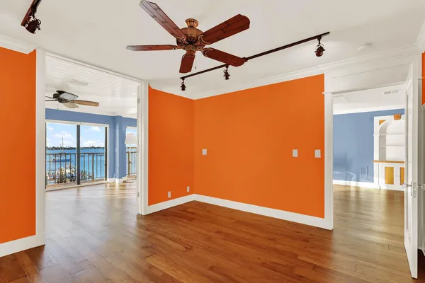 a view of an empty room with wooden floor and a ceiling fan