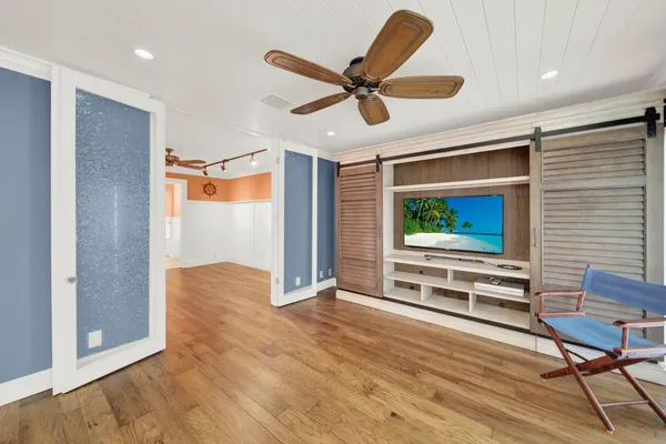 an empty room with wooden floor and a ceiling fan