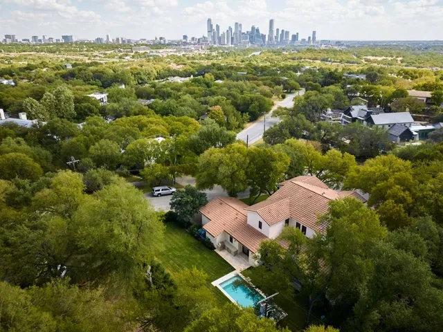 an aerial view of residential houses with outdoor space and trees