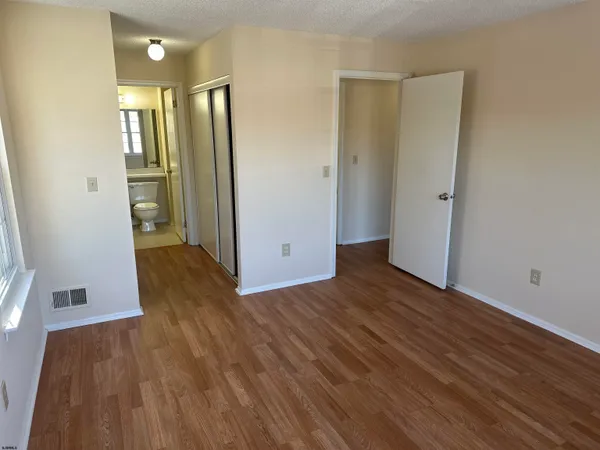 an empty room with wooden floor and a bathroom
