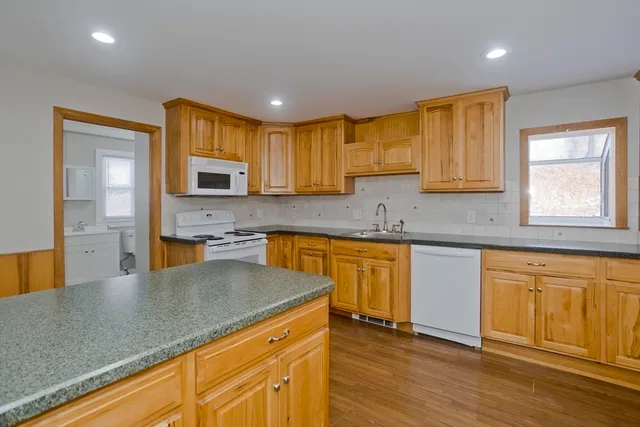 a kitchen with granite countertop a sink cabinets and wooden floor