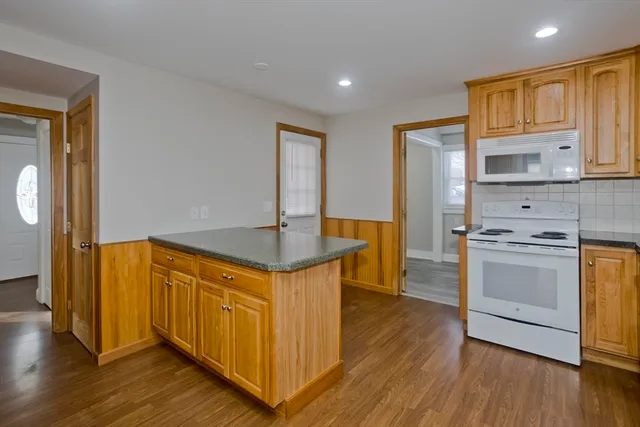 a kitchen with stainless steel appliances granite countertop a sink a stove a refrigerator and island with wooden floor