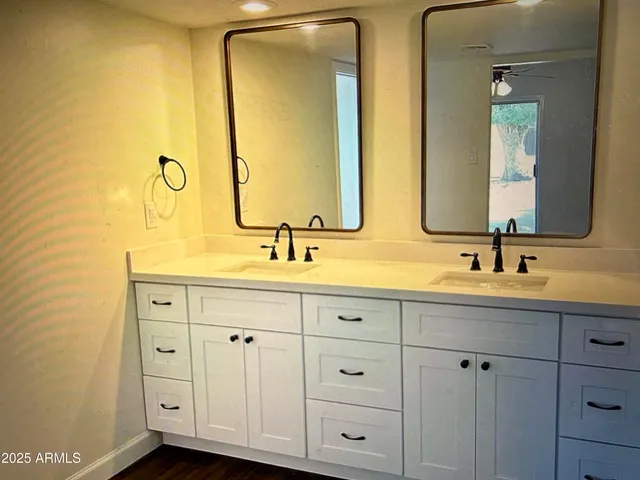 a bathroom with double vanity and a mirror