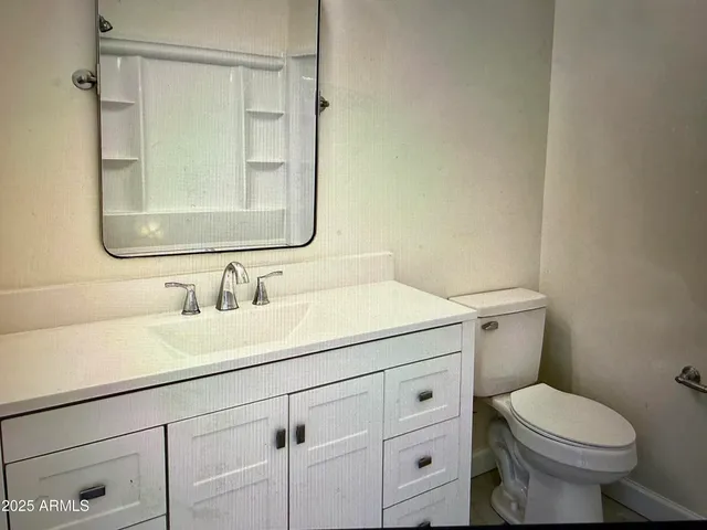 a bathroom with a granite countertop sink mirror vanity and toilet