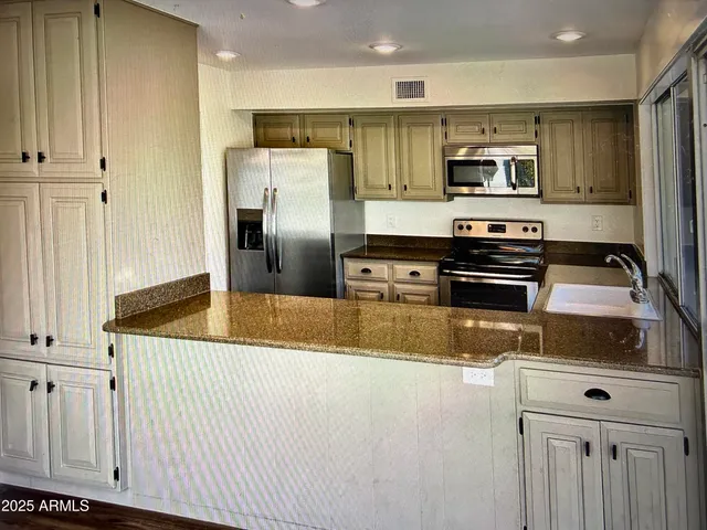 a kitchen with stainless steel appliances granite countertop a refrigerator a stove and a sink