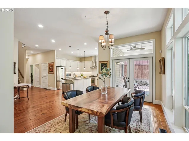 a dining room with stainless steel appliances kitchen island granite countertop a table chairs and a refrigerator