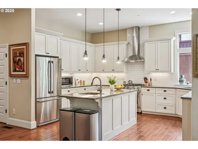 a kitchen with kitchen island granite countertop a sink stainless steel appliances and white cabinets