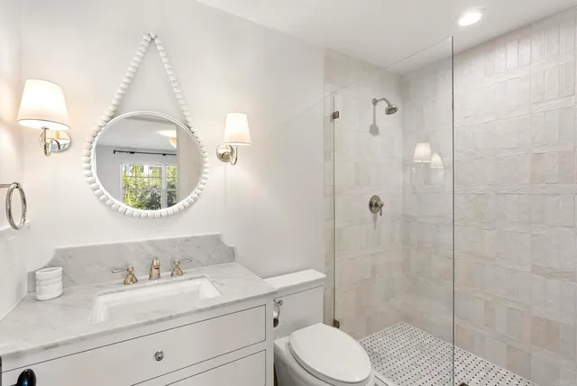 a bathroom with a toilet a sink a mirror a vanity and shower