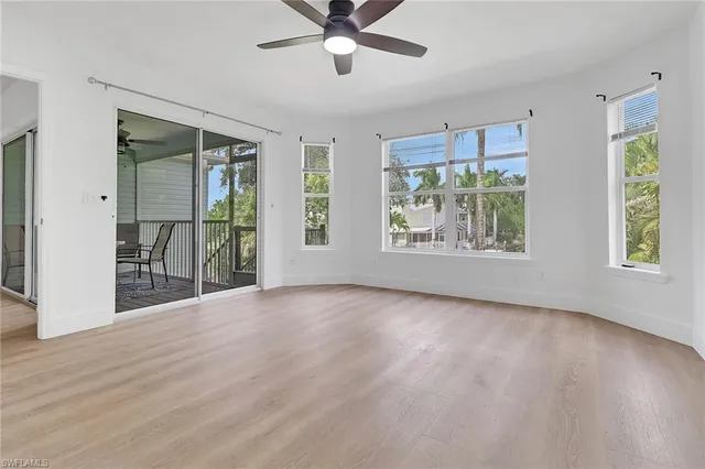 a view of an empty room with a window and wooden floor