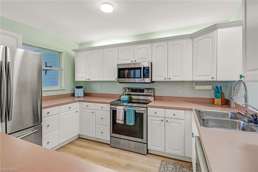 3659 Riviera Circle Bonita Springs, FL 34134 - Photo 20 of 31 a kitchen with white cabinets and stainless steel appliances