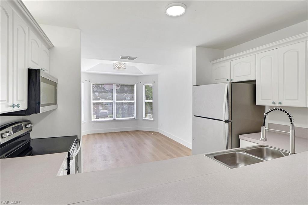 3659 Riviera Circle Bonita Springs, FL 34134 - Photo 4 of 31 a kitchen with a refrigerator sink and cabinets
