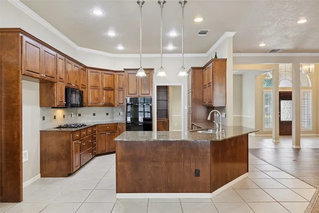 a large kitchen with stainless steel appliances kitchen island granite countertop a refrigerator and a stove top oven