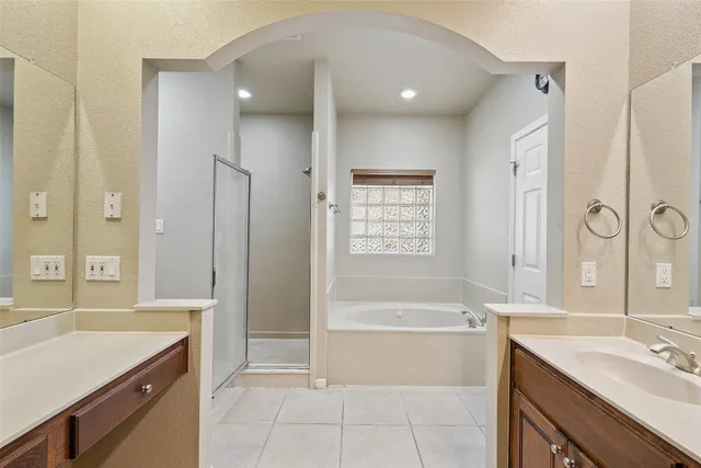 a spacious bathroom with a tub sink shower and a mirror