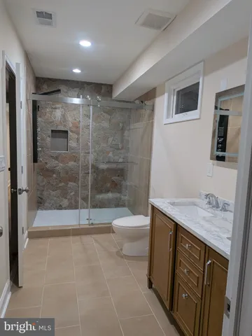 a bathroom with a granite countertop sink a toilet and shower