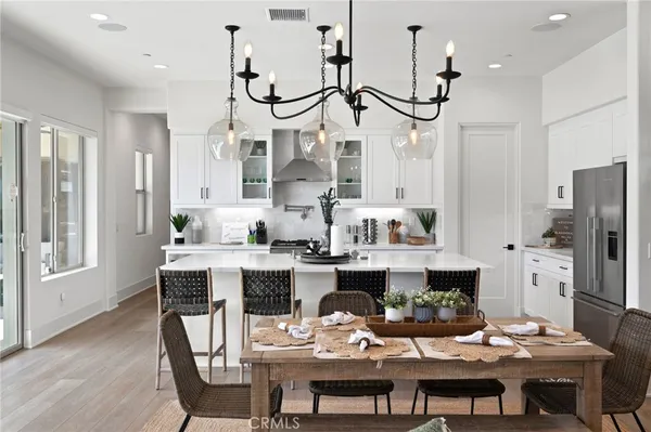 a view of a dining room with furniture a kitchen and chandelier