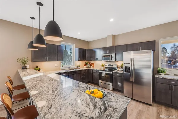 a kitchen with stainless steel appliances granite countertop a sink a stove and a refrigerator