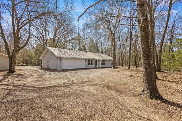 a backyard of a house with large trees and wooden fence
