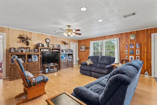 a living room with furniture a flat screen tv and a floor to ceiling window