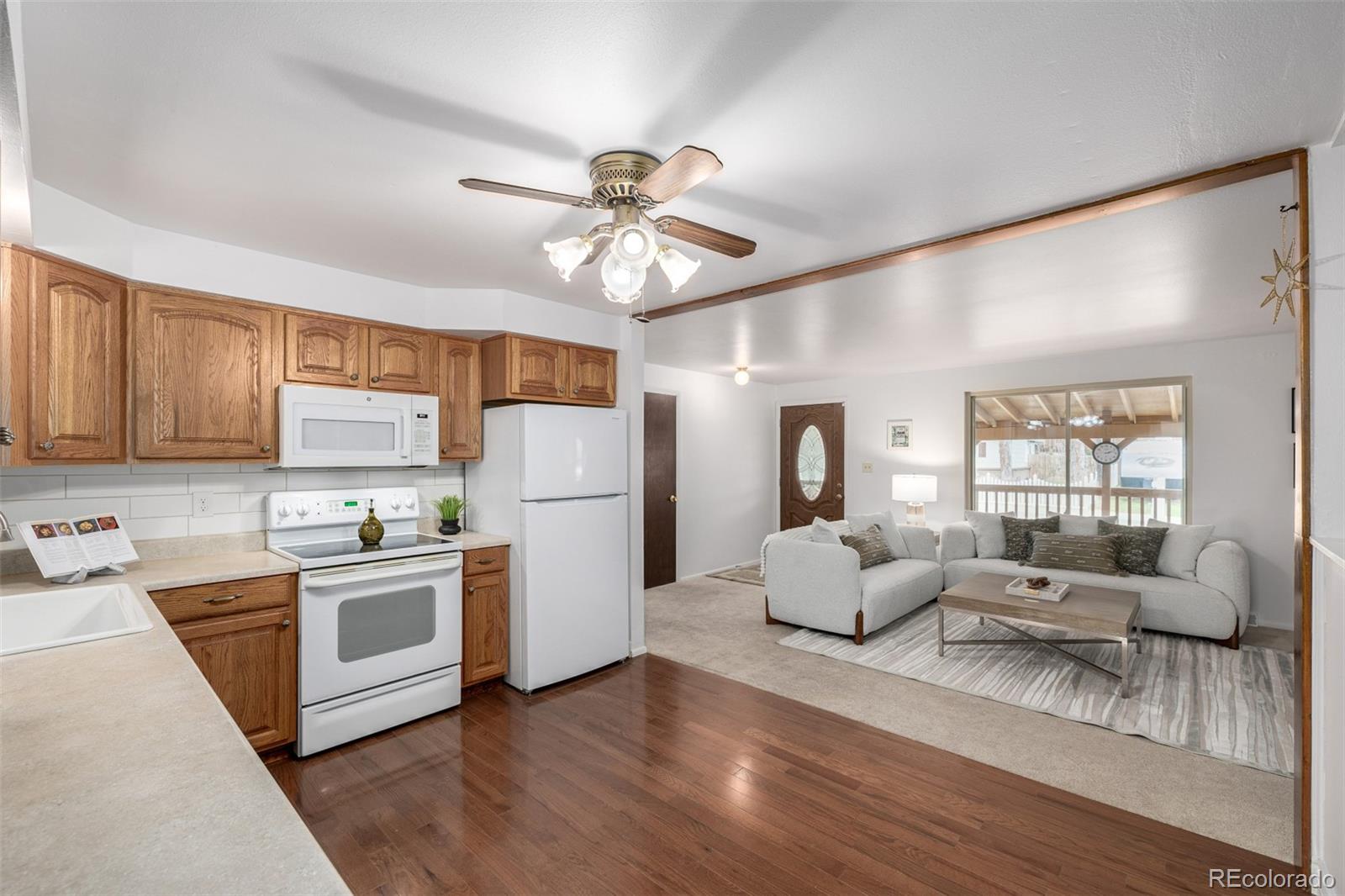 7720 Kendall Street Arvada, CO 80003 - Photo 7 of 45 a kitchen with stainless steel appliances granite countertop a stove top oven a refrigerator a sink and white cabinets with wooden floor