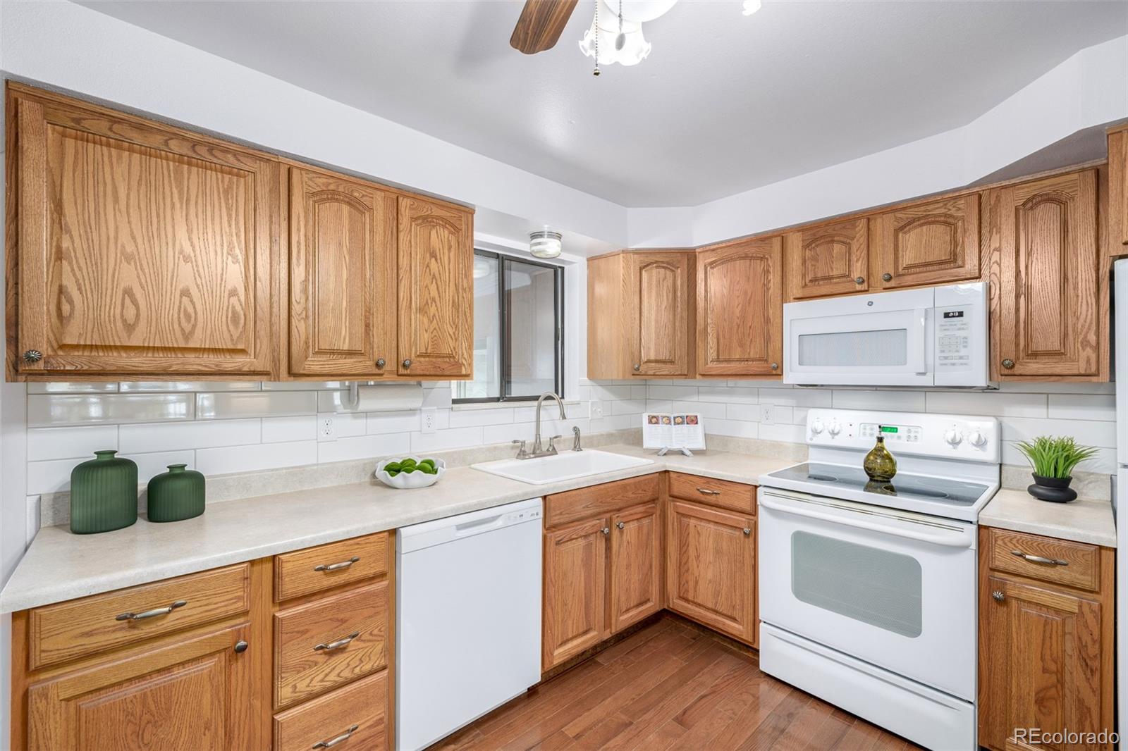 7720 Kendall Street Arvada, CO 80003 - Photo 9 of 45 a kitchen with a sink dishwasher a stove a microwave oven and cabinets with wooden floor