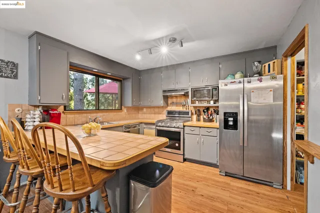a kitchen with stainless steel appliances granite countertop a dining table chairs refrigerator and sink