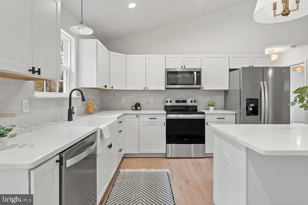 a kitchen with stainless steel appliances a refrigerator sink and white cabinets