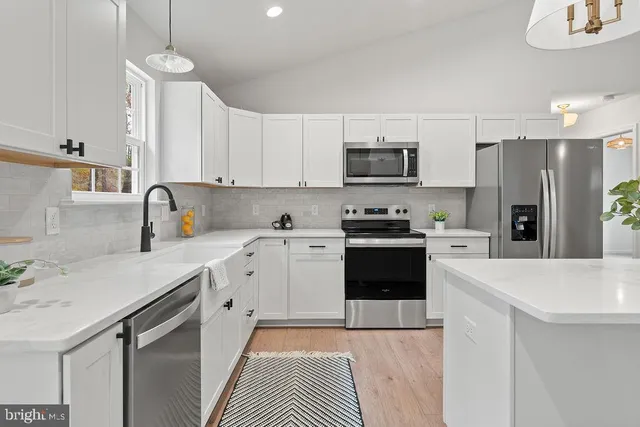 a kitchen with stainless steel appliances a refrigerator sink and white cabinets