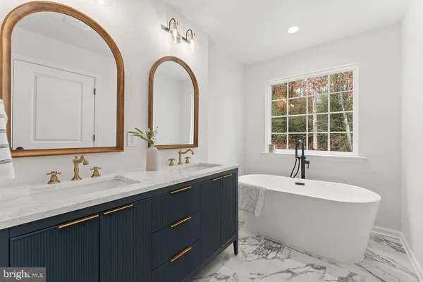 a bathroom with a double vanity sink a mirror and a bathtub