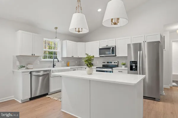 a kitchen with stainless steel appliances a sink a stove a refrigerator cabinets and chairs