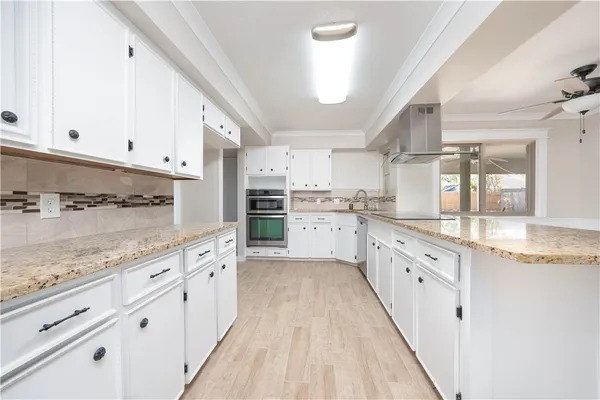 a large kitchen with stainless steel appliances granite countertop a lot of counter space and wooden floors