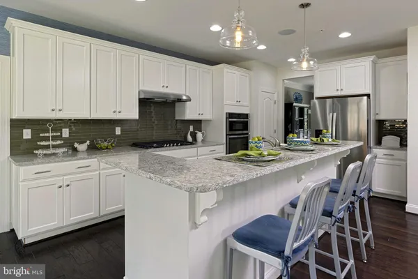 a kitchen with kitchen island granite countertop a table chairs sink and cabinets