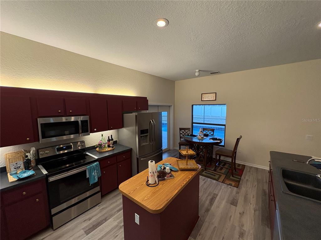 2810 Highview Bend Lakeland, FL 33812 - Photo 17 of 35 a kitchen with stainless steel appliances a stove a refrigerator a sink dishwasher and a stove with wooden floor