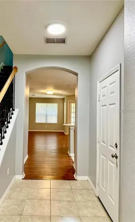 a view of a hallway to an empty room with wooden floor and a living room