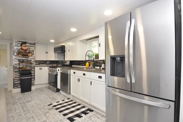 a kitchen with a refrigerator and white cabinets