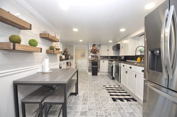 a kitchen with stainless steel appliances kitchen island granite countertop a refrigerator a sink and white cabinets