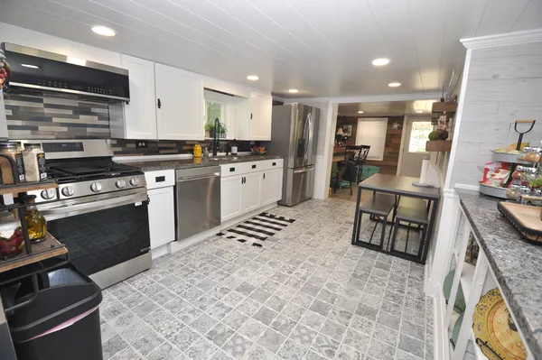 a kitchen with stainless steel appliances granite countertop a stove a sink and a refrigerator