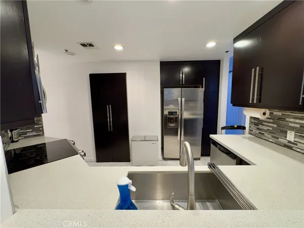 a kitchen with stainless steel appliances kitchen island granite countertop a refrigerator and a sink