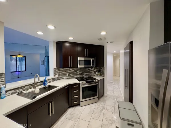 a large kitchen with stainless steel appliances a sink and a refrigerator