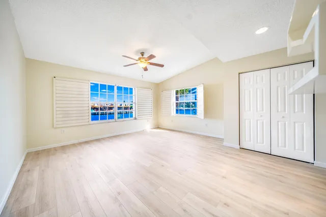 an empty room with windows and chandelier fan