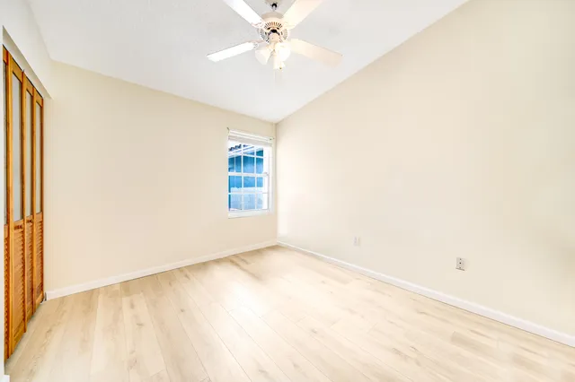 an empty room with a window and a ceiling fan