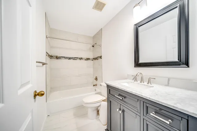 a bathroom with a granite countertop sink a toilet and shower
