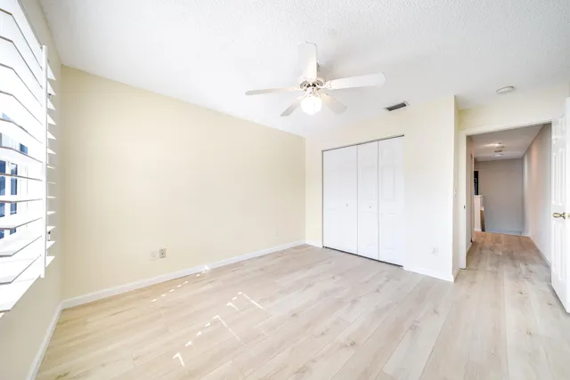 a view of empty room with wooden floor and fan