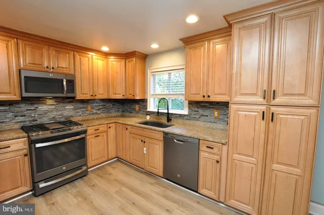 a kitchen with stainless steel appliances granite countertop a stove a sink and a microwave