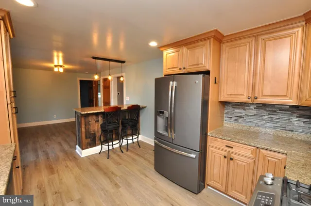 a kitchen with stainless steel appliances granite countertop a refrigerator microwave and wooden floor