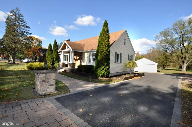 a view of a white house with a yard plants and large tree